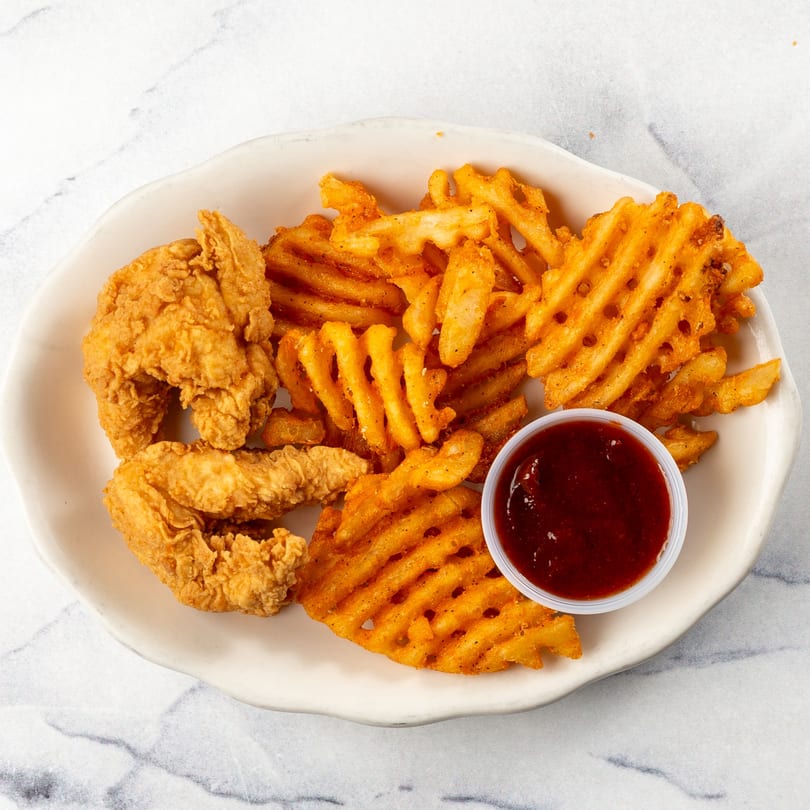 Crispy chicken tenders and seasoned waffle fries with a side of dipping sauce on a white plate.